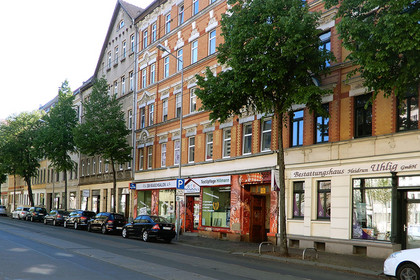 Straßenzug der Gorkistraße mit mehrstöckigen Häusern, Straßenbäumen und parkenden Autos.