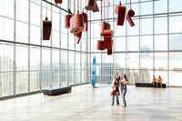 Kunstinstallation bestehen aus von der Decke hängenden übergroßen Trillerpfeifen und Ghettoblaster im Museum der bildenden Künste. Zwei Besucher betrachten sich diese. 