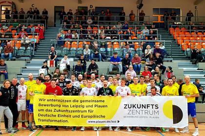 Zwei Handballmannschaften stehen in hinter einem Banner zum Zukunftszentrum