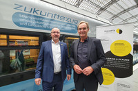 Plauens Oberbürgermeister Steffen Zenner und Leipzigs Oberbürgermeister im Anzug stehen vor einem blauen Zug