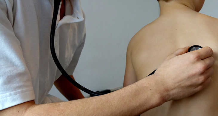 Arzt der den Rücken eines Kindes mit einem Stetoskop abhört
