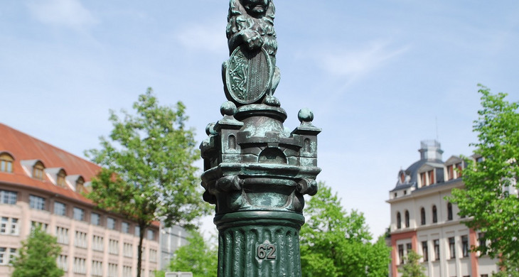 Metallskulptur eines Leipziger Löwen mit Stadtwappen auf einer Säule am Listplatz.