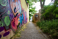 Blick auf einen Weg, der entlang einer mit buntem Graffiti besprühten Hauswand führt