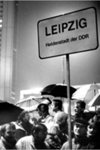 Schwarz-Weiß Foto einer Demonstration im Herbst 89 mit einem Schild "Leipzig - Heldenstadt der DDR"