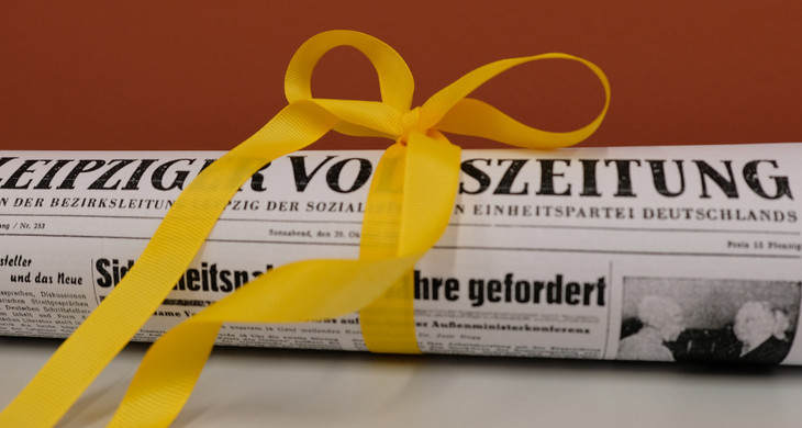 Kopie der Leipziger Volkszeitung, eingerollt mit gelbem Schleifenband