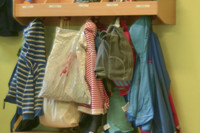 Schulsachen und Kinderkleidungen hängen an mehreren Kleiderhaken