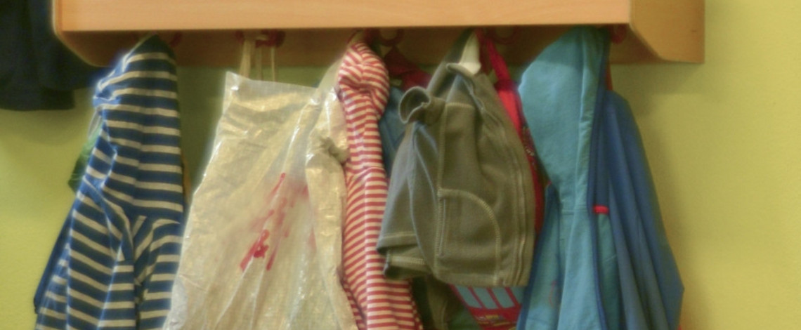 Schulsachen und Kinderkleidungen hängen an mehreren Kleiderhaken