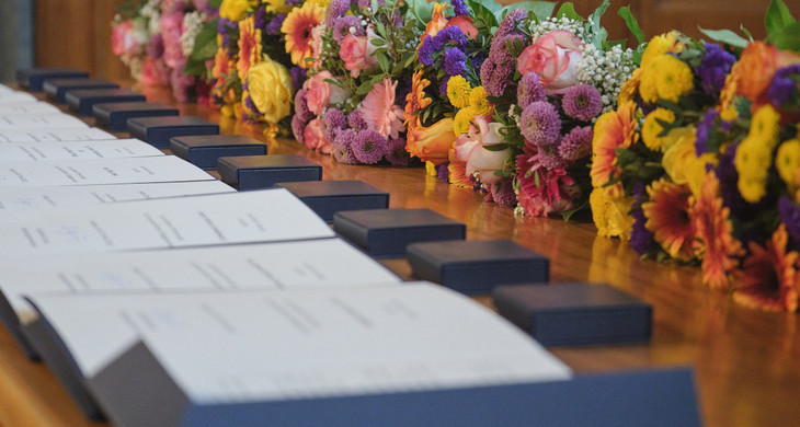 Auf einem Tisch liegen aufgereiht Urkunden und Blumensträuße zur Verleihung der Goldenen Ehrennadel der Stadt Leipzig