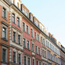 Zu sehen ist eine Häuserfront mit farbigen Fassaden in Rottönen und Verzierungen.