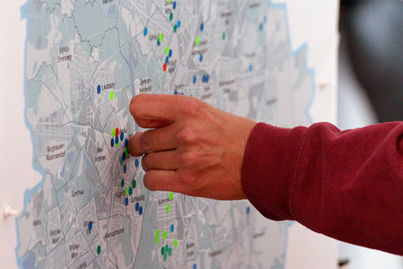 Eine Hand klebt Punkte auf eine Stadtkarte.