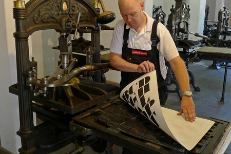 Druck an einer Kniehebelpresse im Museum für Druckkunst Leipzig