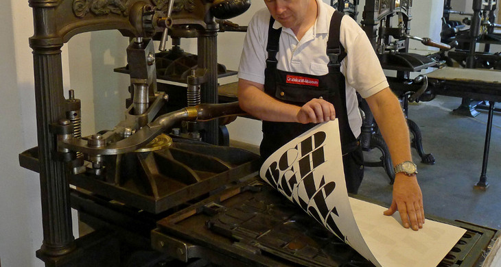 Druck an einer Kniehebelpresse im Museum für Druckkunst Leipzig