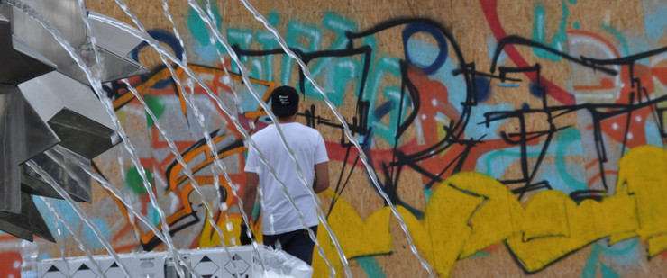 Junger Mann besprüht eine Graffiti-Wand