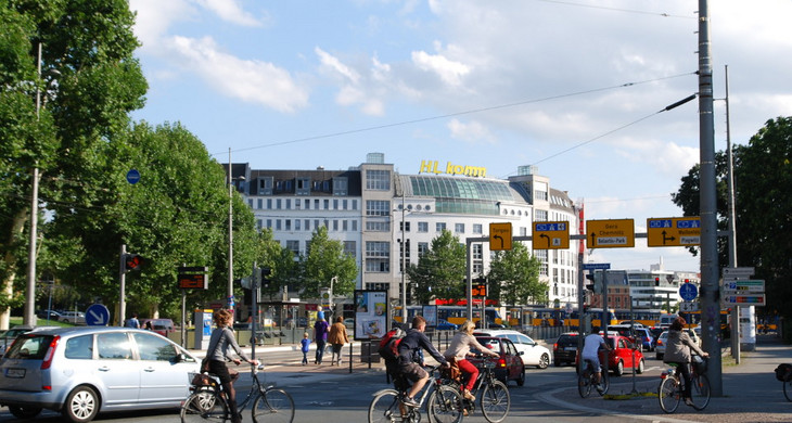 Fahrradfahrer und Autofahrer auf dem Leipziger Innenstadtring. Im Hintergrund fährt eine Straßenbahn.