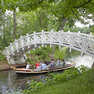 Im Wörlitzer Park fahren Personen in einem Boot unter einer Füßgängerbrücke hindurch.