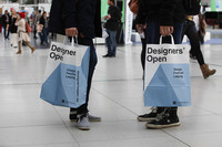 Zwei Menschen tragen Papiertüten mit Designers Open Logo
