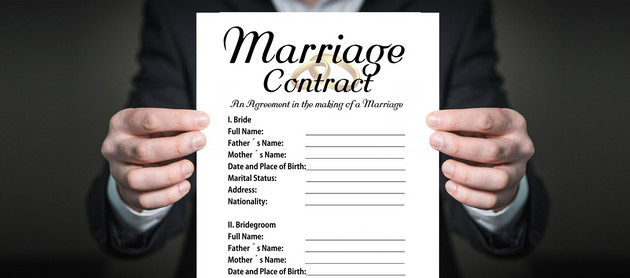 Zwei Hände halten einen Zettel mit einer englischen Heiratsvereinbarung 
