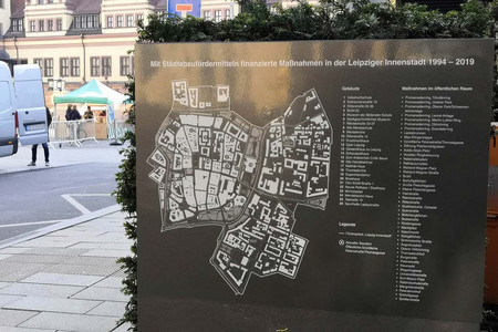 Auf einer Stahlplatte ist die Gebietsgrenze des Fördergebietes Innenstadt zu sehen. Im Hintergrund sieht man den Markt mit dem Alten Rathaus.