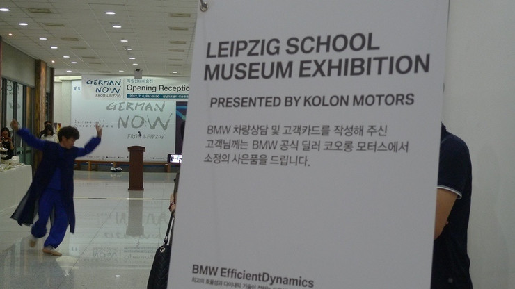 Blick auf das Roll Up mit dem Schriftzug Neue Leipziger Schule in Seoul zur Ausstellungseröffnung auf Deutsch und Koreanisch