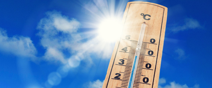 Thermometer, das 38°C anzeigt vor blauem Himmel und gleißend heller Sonne