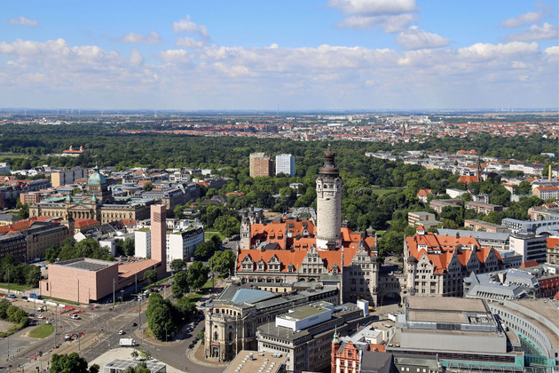 Blick aus der Vogelperspektive auf einen Teil der Leipziger Innenstadt mit dem Neuen Rathaus und seinem prägnanten Rathausturm. Dahinter auch viele Bäume.