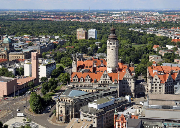 Blick aus der Vogelperspektive auf einen Teil der Leipziger Innenstadt mit dem Neuen Rathaus und seinem prägnanten Rathausturm. Dahinter auch viele Bäume.
