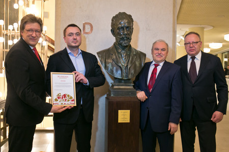 Vier Herren stehen um eine Bronzebüste des Musikers Tschaikowski. Einer hält eine Urkunde.