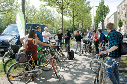 Viele Leute mit Fahrrädern stehen auf einem Fußweg und unterhalten sich.