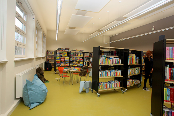 Blick in die neue Kinderbibliothek der Bibliothek Plagwitz, großer Raum mit grünem Fußboden, vielen Regalen, kleinen Tischen, bunten Stühlen und Sitzsäcken.