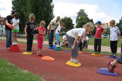 Kinder beim Geschicklichkeitsspiel auf dem Sportplatz