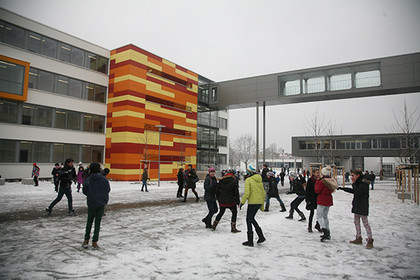 Schüler spielen auf dem Schulhof des neugebauten Reclam-Gymnasiums im Schnee.