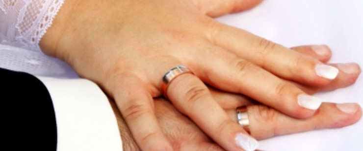 Hände von Braut und Bräutigam mit Eheringen