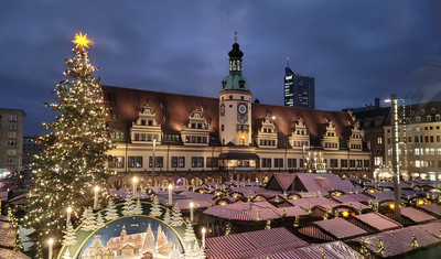 Blick über die Dächer der Weihnachtsmarktbuden mit erleuchtetem Weihnachtsbaum und altem Rathaus zu Leipzig.