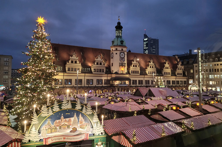 Blick über die Dächer der Weihnachtsmarktbuden mit erleuchtetem Weihnachtsbaum und altem Rathaus zu Leipzig.