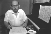 Hans Eisler mit einem Notenblatt und einen Klavier beim Komponieren.