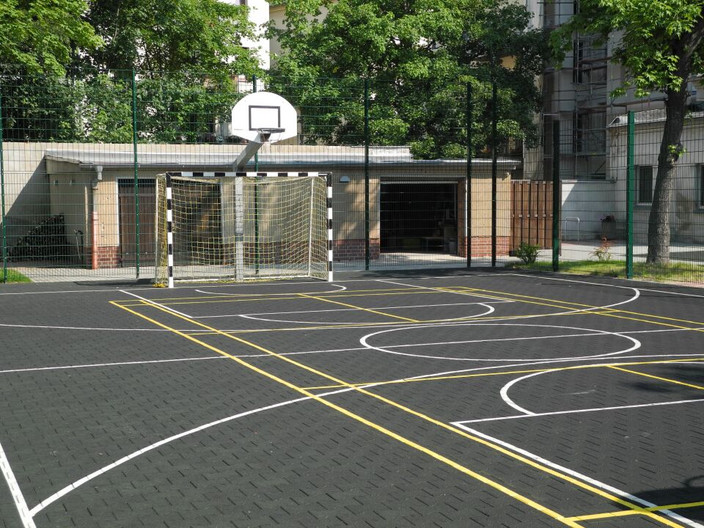Umzäunte und markierte Außen-Spielflächen mit kleinem Fußballtor und darüber einem Basketballkorb.