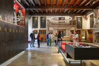 Besucherinnen und Besucher stehen im Eingangsbereich des Alten Rathauses. An der Wand hängen Bilder und andere Ausstellungsstücke.