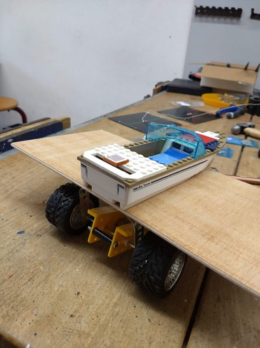 Selbstgebautes Fahrzeug aus Lego und Holzplatte auf einem Tisch