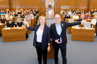 Personalamtsleiterin Claudia Franko und Verwaltungsbürgermeister Ulrich Hörning zeigen mit ihren Händen nach hinten in den Saal. Auf den vielen Plätzen sitzen neue Auszubildende.