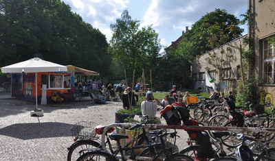 Ein Fest auf dem Polygraphplatz, wo einige Menschen zusammen gekommen sind. Auf dem Platz stehen Fahrräder und der Container vom Sphere Radio. 