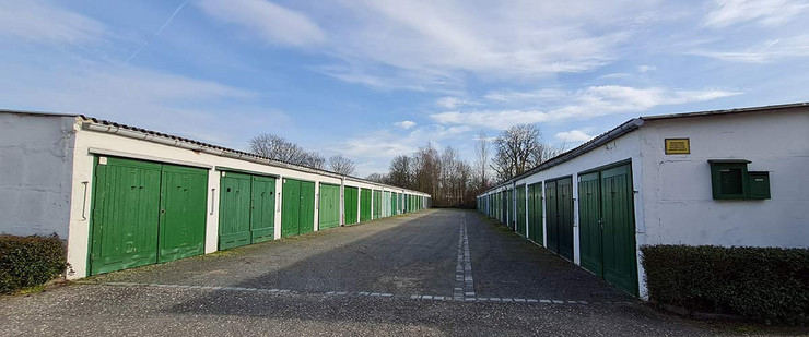 Zwei Garagenzeilen links und recht mit weißen Wänden und grünen Holztoren