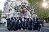 Junge Absolventen werfen ihre Magisterhüte in die Luft vor der Thomaskirche.
