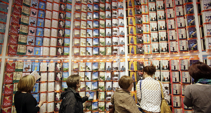 Vier Leserinnen stehen vor einer meterhohen Bücherwand