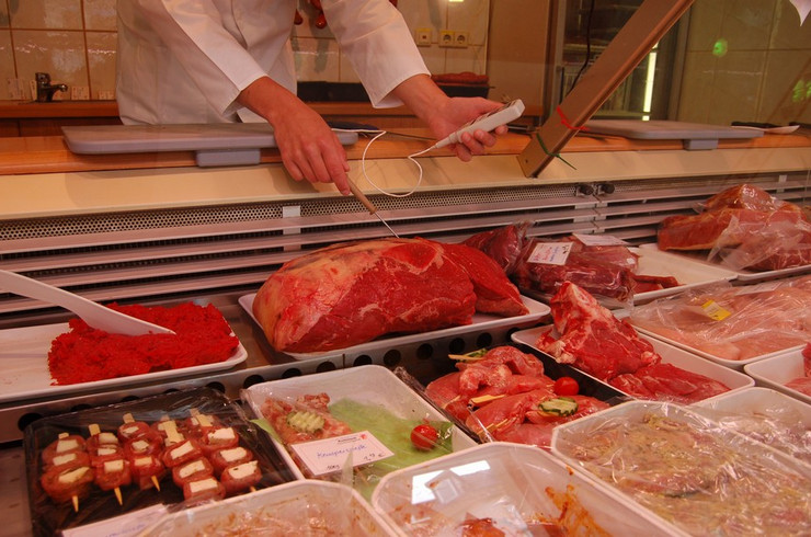Temperaturmessung einer Fleischtheke mit Auslagen von Fleisch, Fleischerzeugnissen und Schalen mit Salaten durchgeführt von einem Lebensmittelkontrolleur