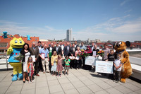 Eine Gruppe von Menschen mit Urkunden zum Familienfreundlichkeitspreis über den Dächern von Leipzig.
