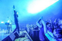 Ein Musiker steht mit erhobenen Armen auf einer Bühne bei der Audio Invasion. Das Publikum klatscht und ist begeistert. 