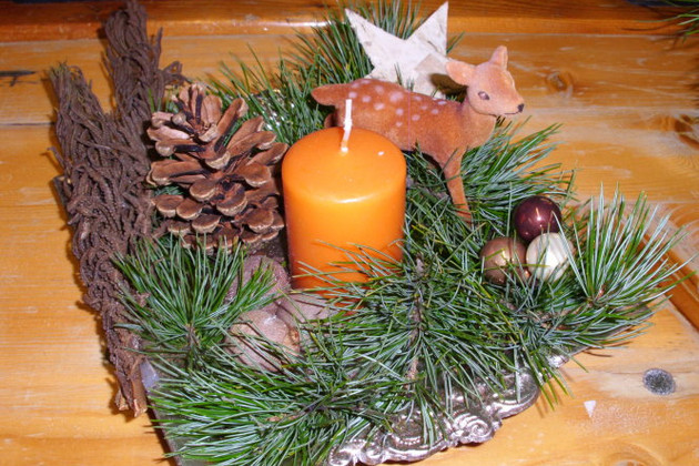 Ein selbst gestaltetes Adventsgesteck mit Kerze, Zapfen und Sternen