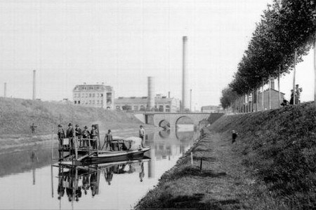 Historische Aufnahme vom Bau des Karl-Heine-Kanals mit Industriegebäuden im Hintergrund und Bauarbeitern auf einem Boot