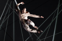 Ein junger Mann im Spotlicht springt und tanzt im dunklen Bühnenhintergrund in die Luft