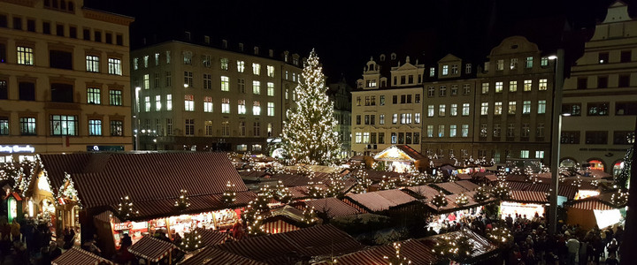 Leipziger Weihnachtsmarkt auf dem Marktplatz in der Nacht. Um die beleuchteten Stände tummeln sich zahlreiche Menschen.